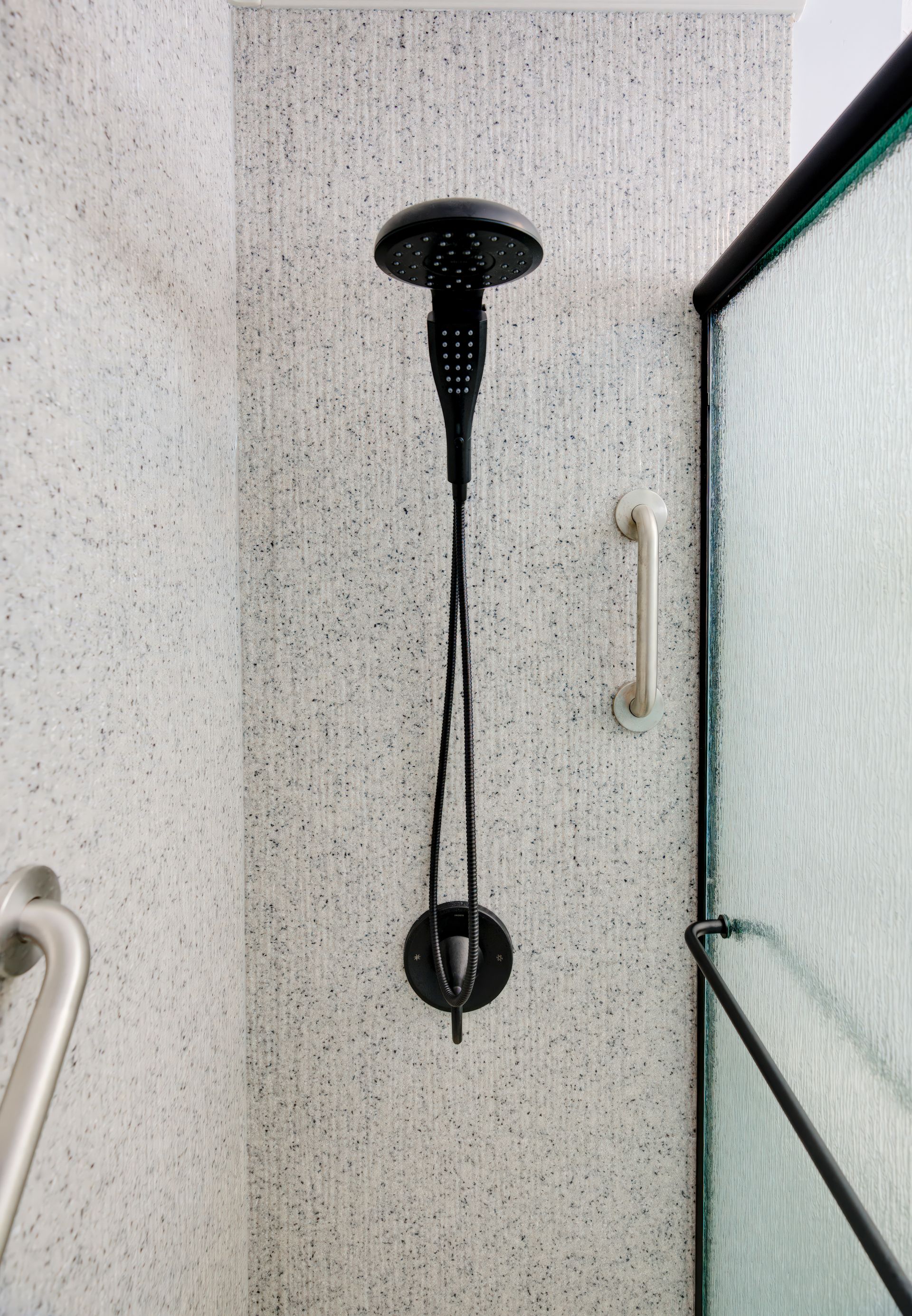 A shower with a black shower head and a glass door