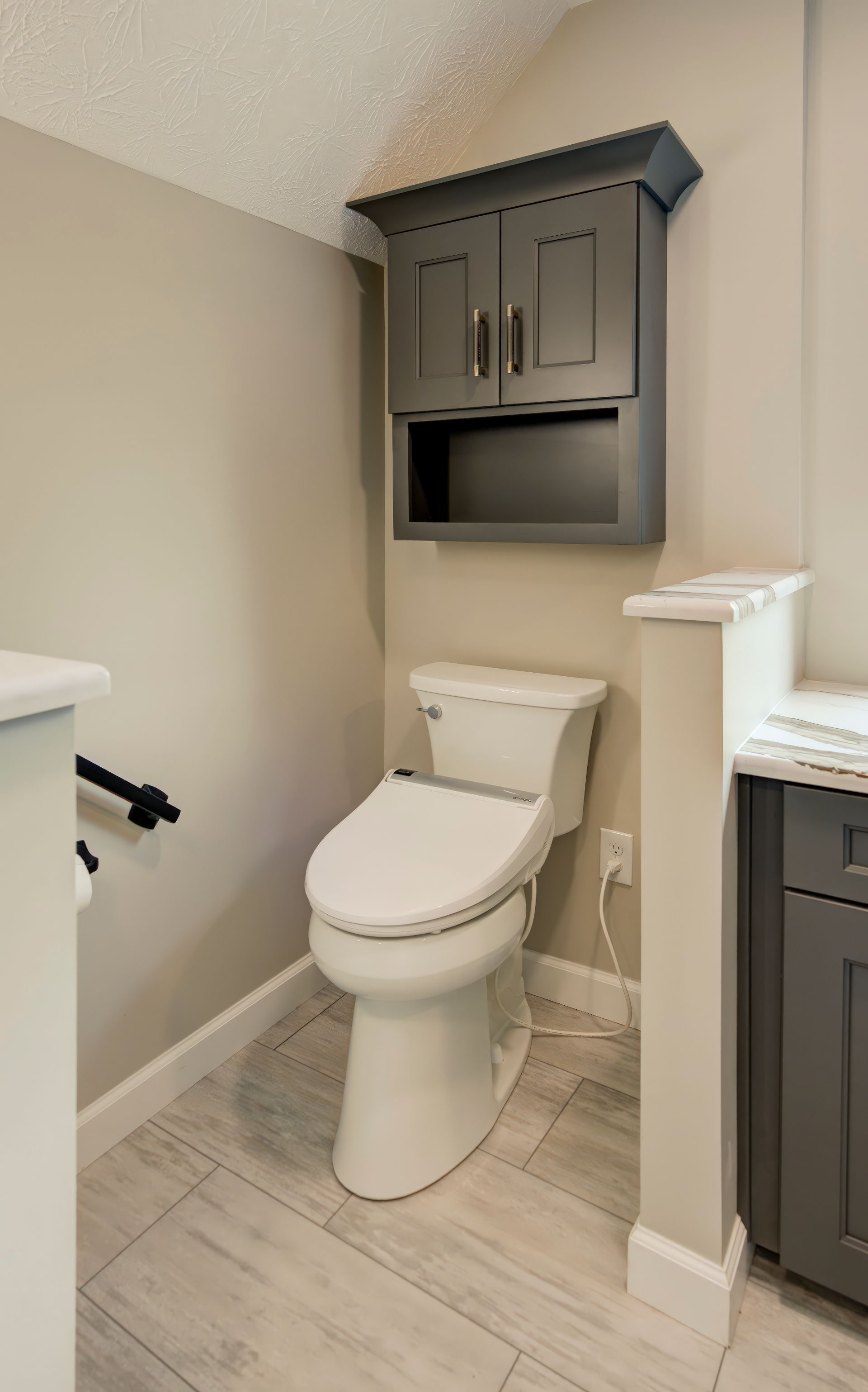A bathroom with a toilet, sink and cabinets.