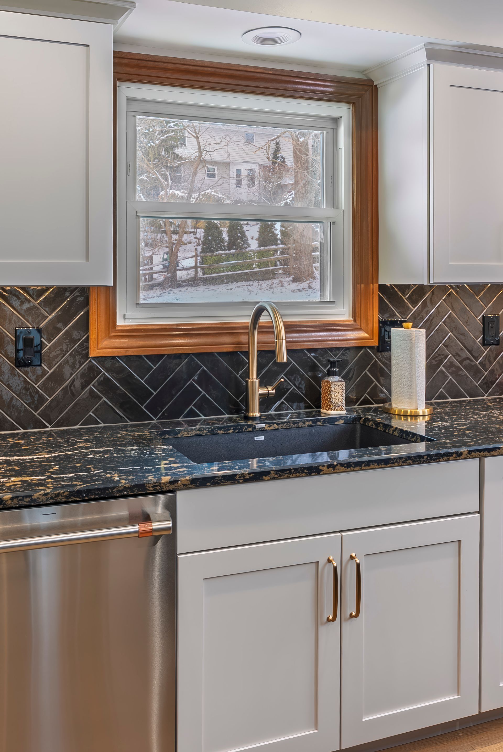 A kitchen with a sink, dishwasher, and window.