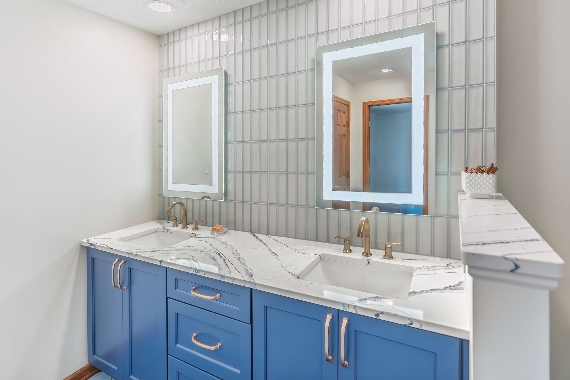 A bathroom with two sinks, two mirrors and blue cabinets.