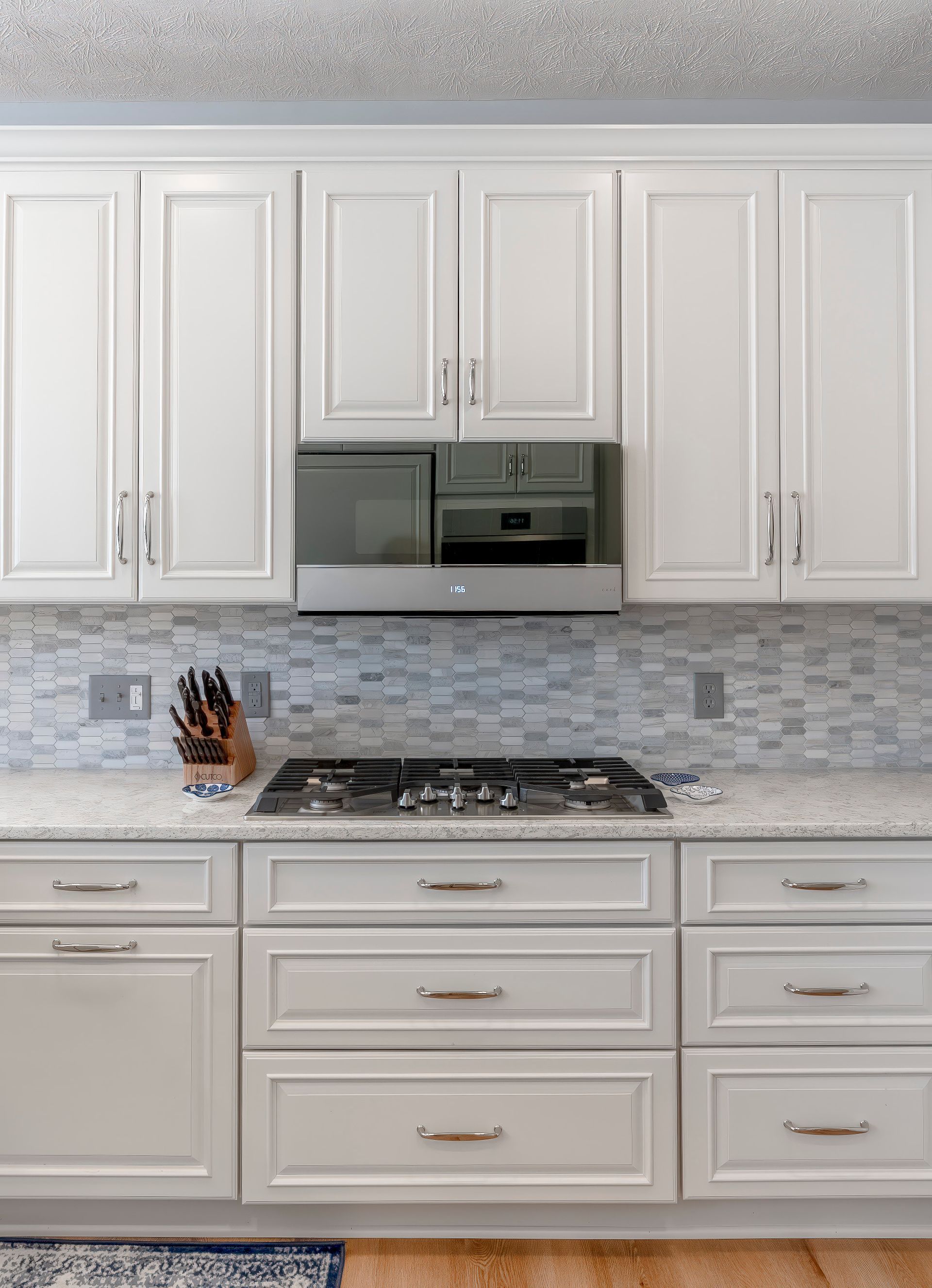 A kitchen with white cabinets and a stove top oven.