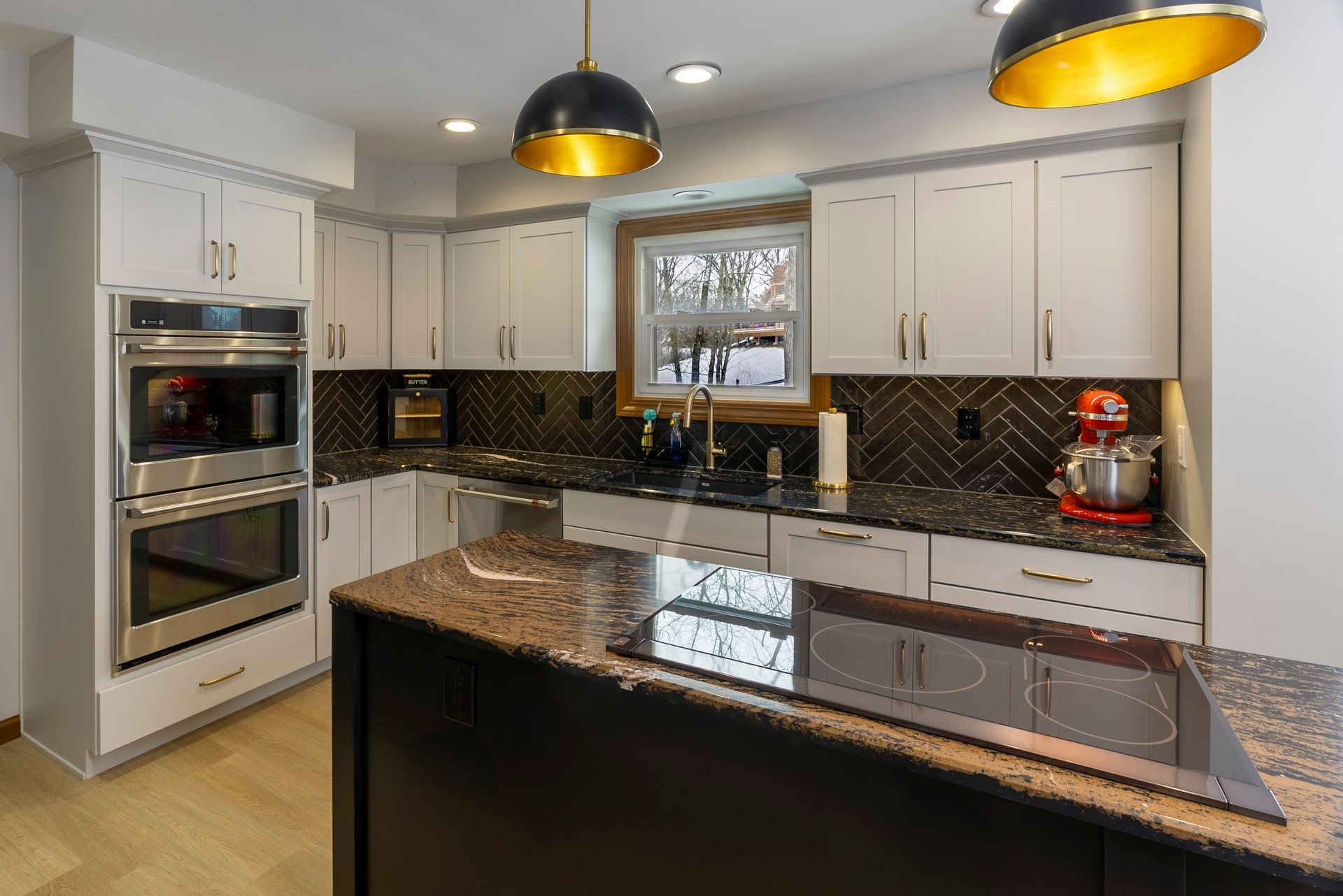 A kitchen with white cabinets, granite counter tops, stainless steel appliances and a large island.