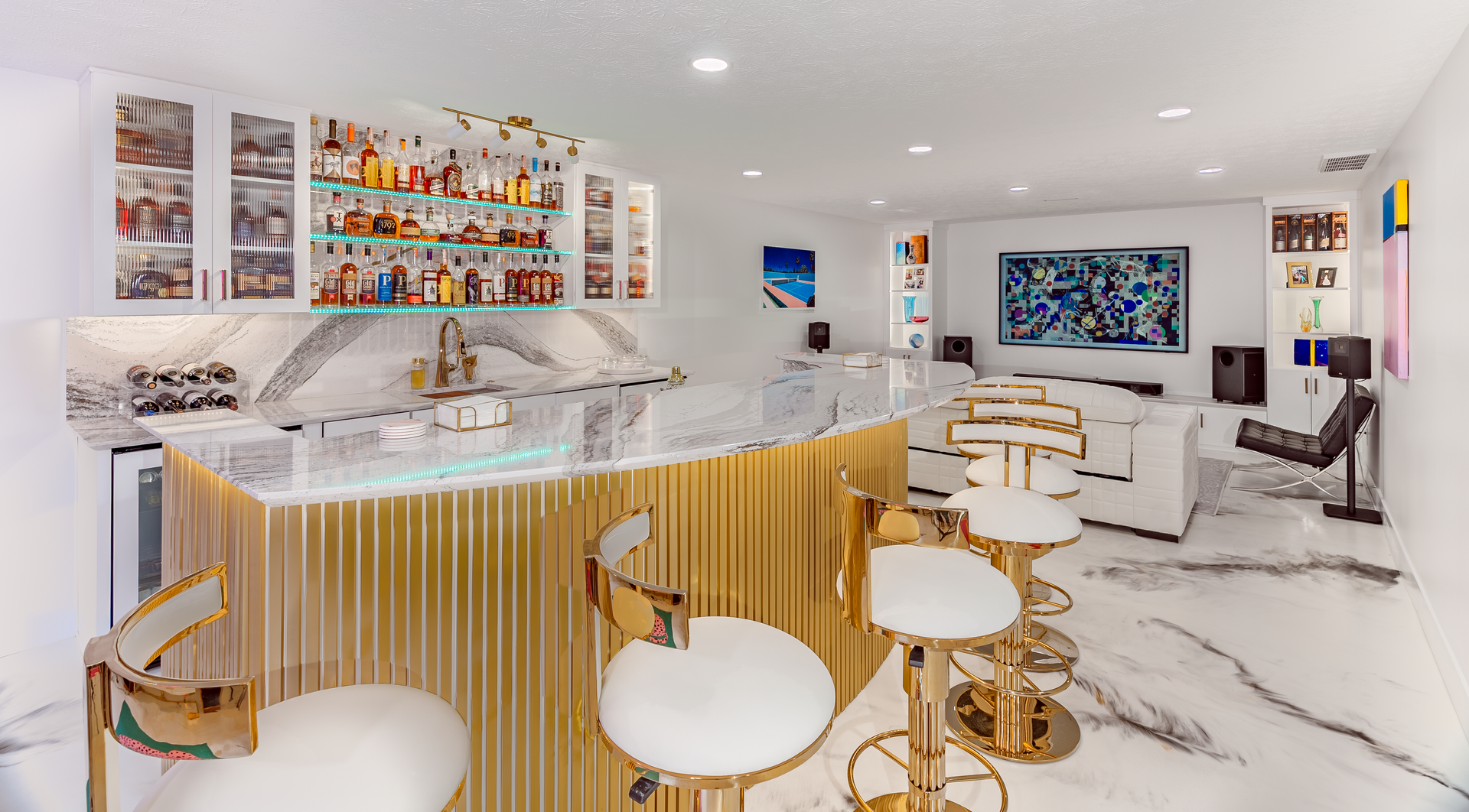Luxurious home bar with gold accents, marble counter, and white seating.