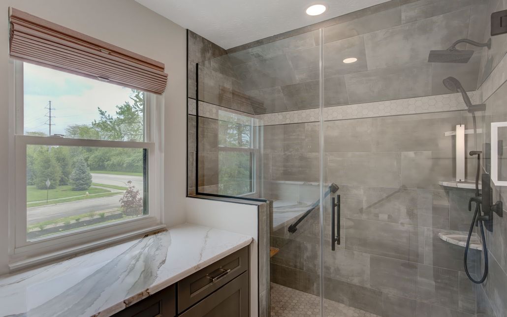 A bathroom with a walk in shower and a window.