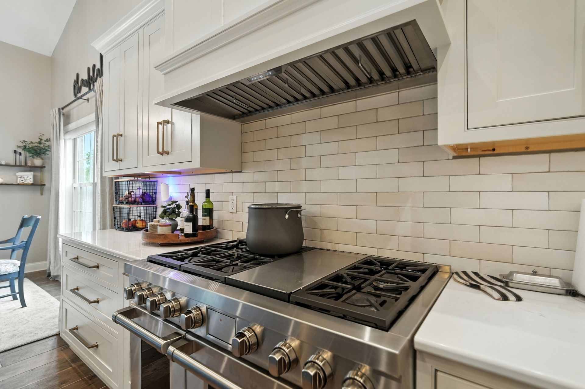 Stainless steel range in a white kitchen with white tiled backsplash.