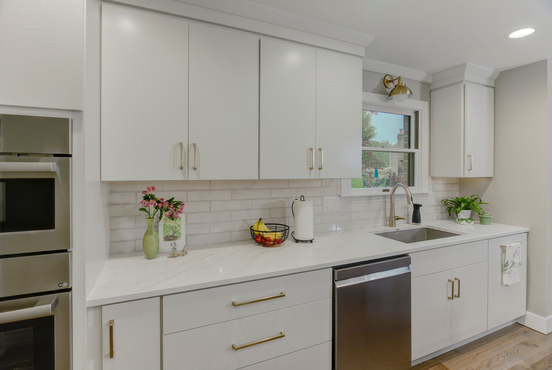 White kitchen with cabinets, countertops, and a stainless steel dishwasher.