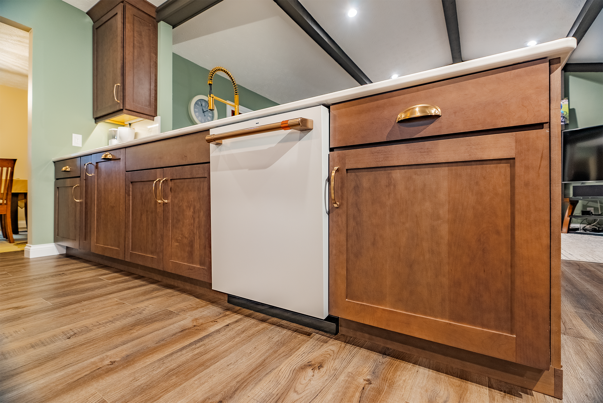 Kitchen island with wood cabinets, white dishwasher, and gold hardware.