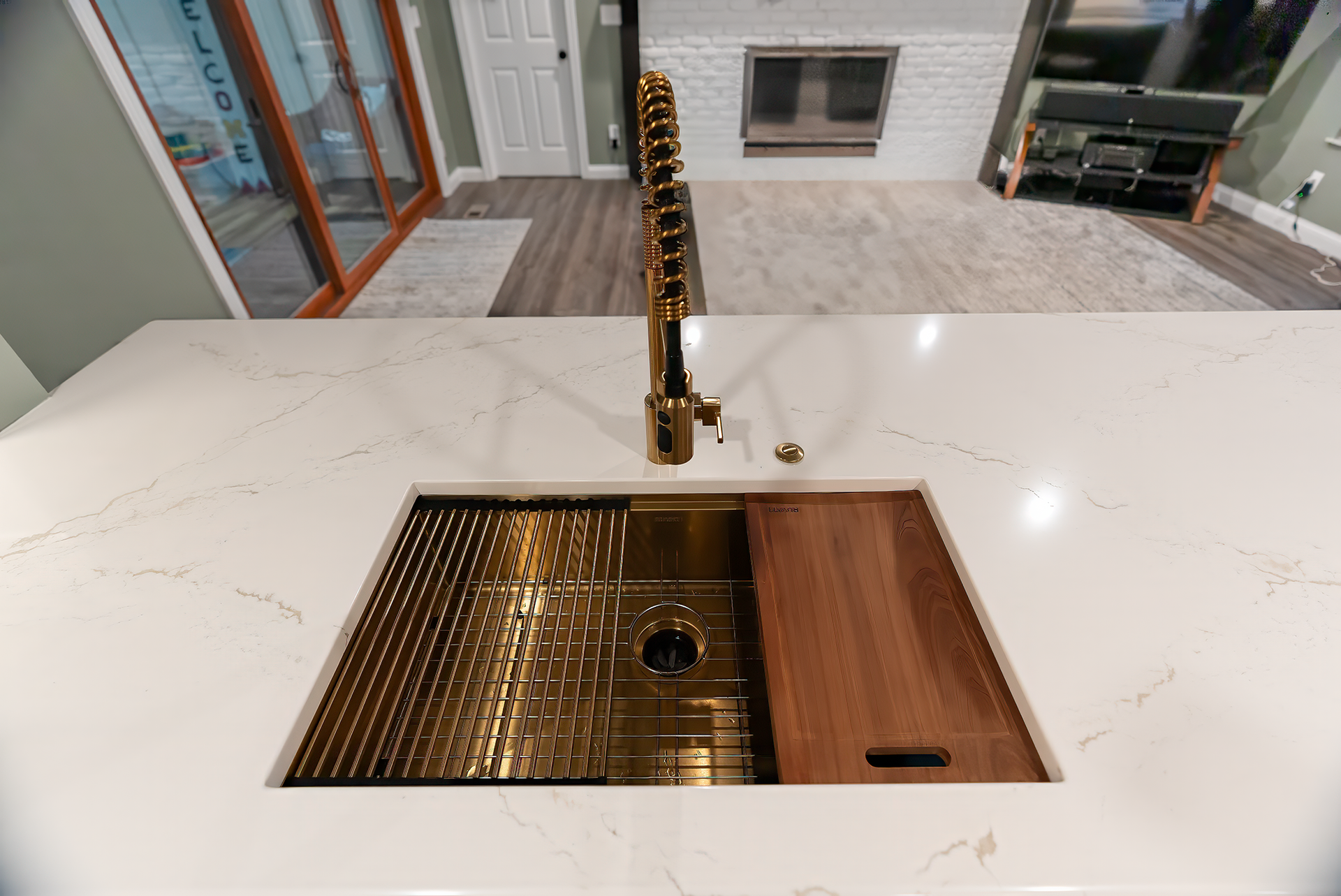 Gold kitchen sink with cutting board, on white countertop.