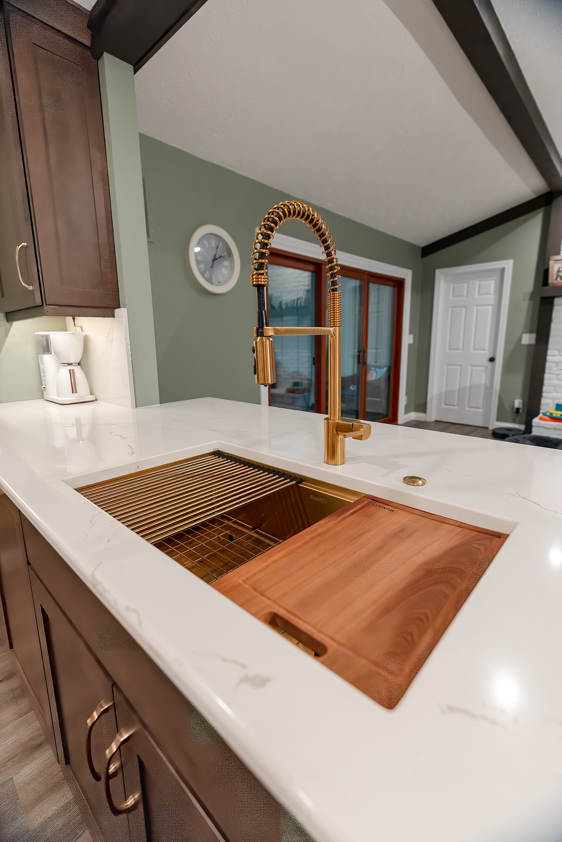 Copper kitchen sink with gold faucet and white countertop.