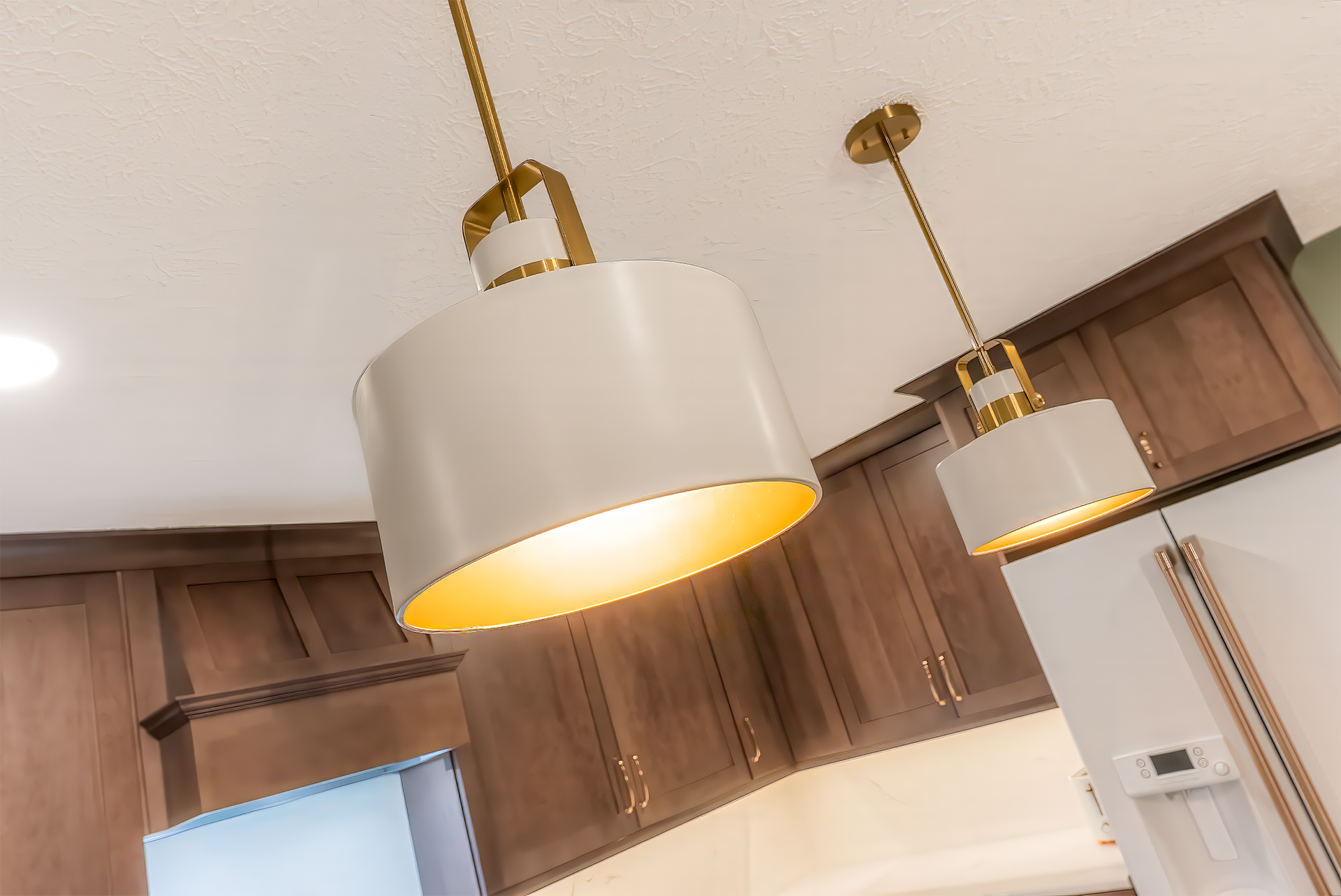 Two white and gold pendant lights hanging in a kitchen.