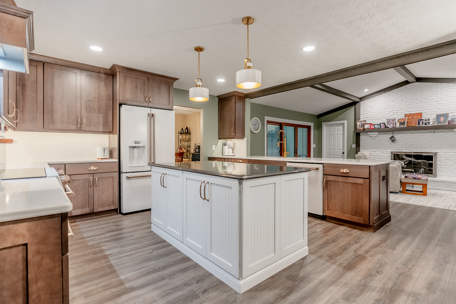 Spacious kitchen with wood cabinets, white island, and a fireplace in the background.