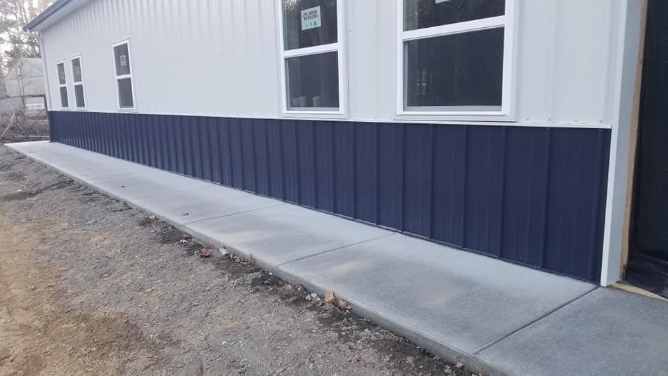 Exterior of building with blue siding below windows and concrete sidewalk.