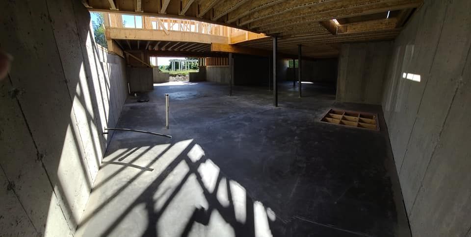 Unfinished basement with concrete floor and walls; shadows cast by sunlight.