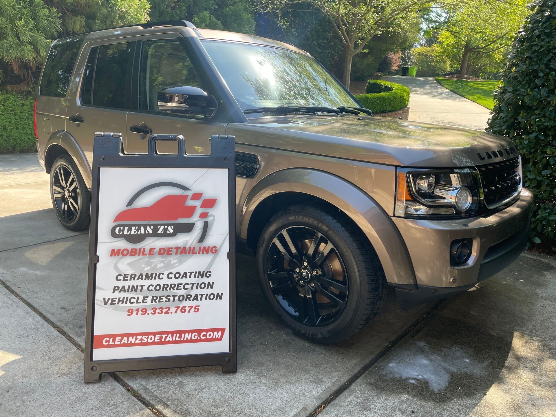 A brown SUV next to a sign advertising 
