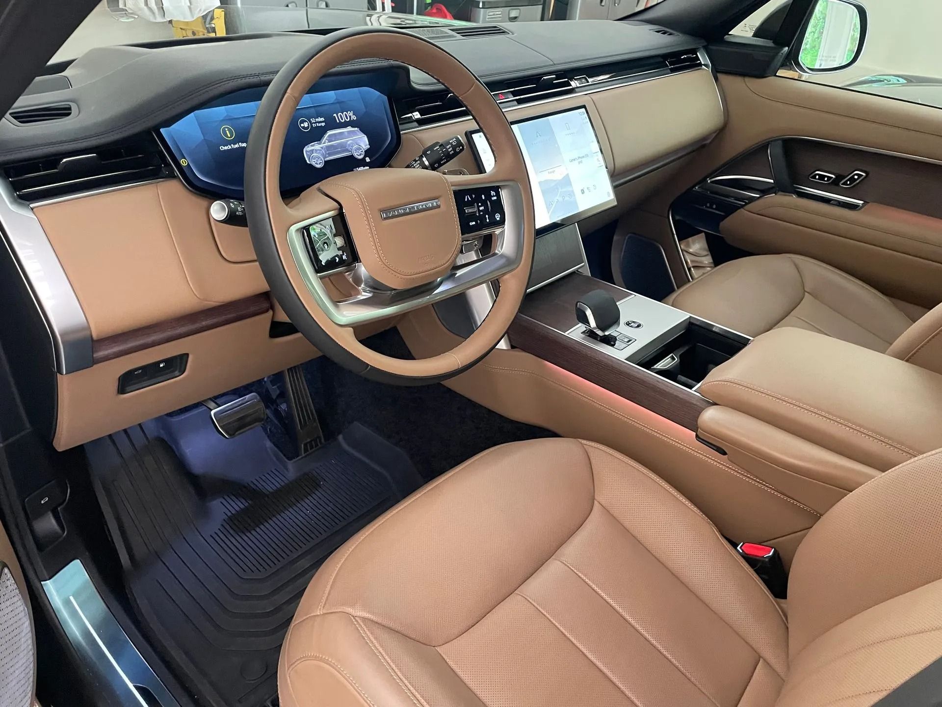 Tan interior of a Range Rover: leather seats, steering wheel, digital displays, and console.