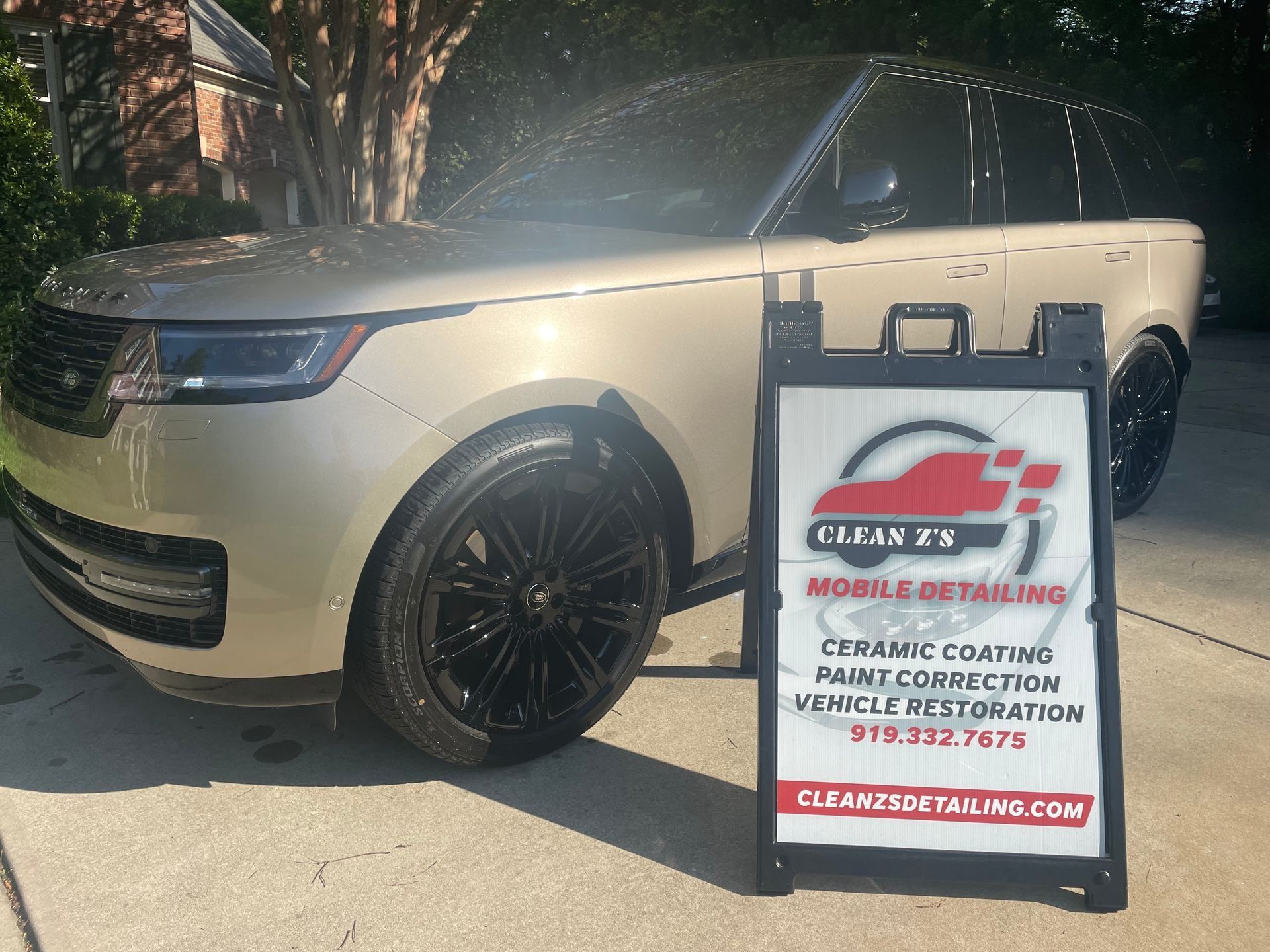 Gold Range Rover with black wheels; Clean FX Mobile Detailing sign in front.