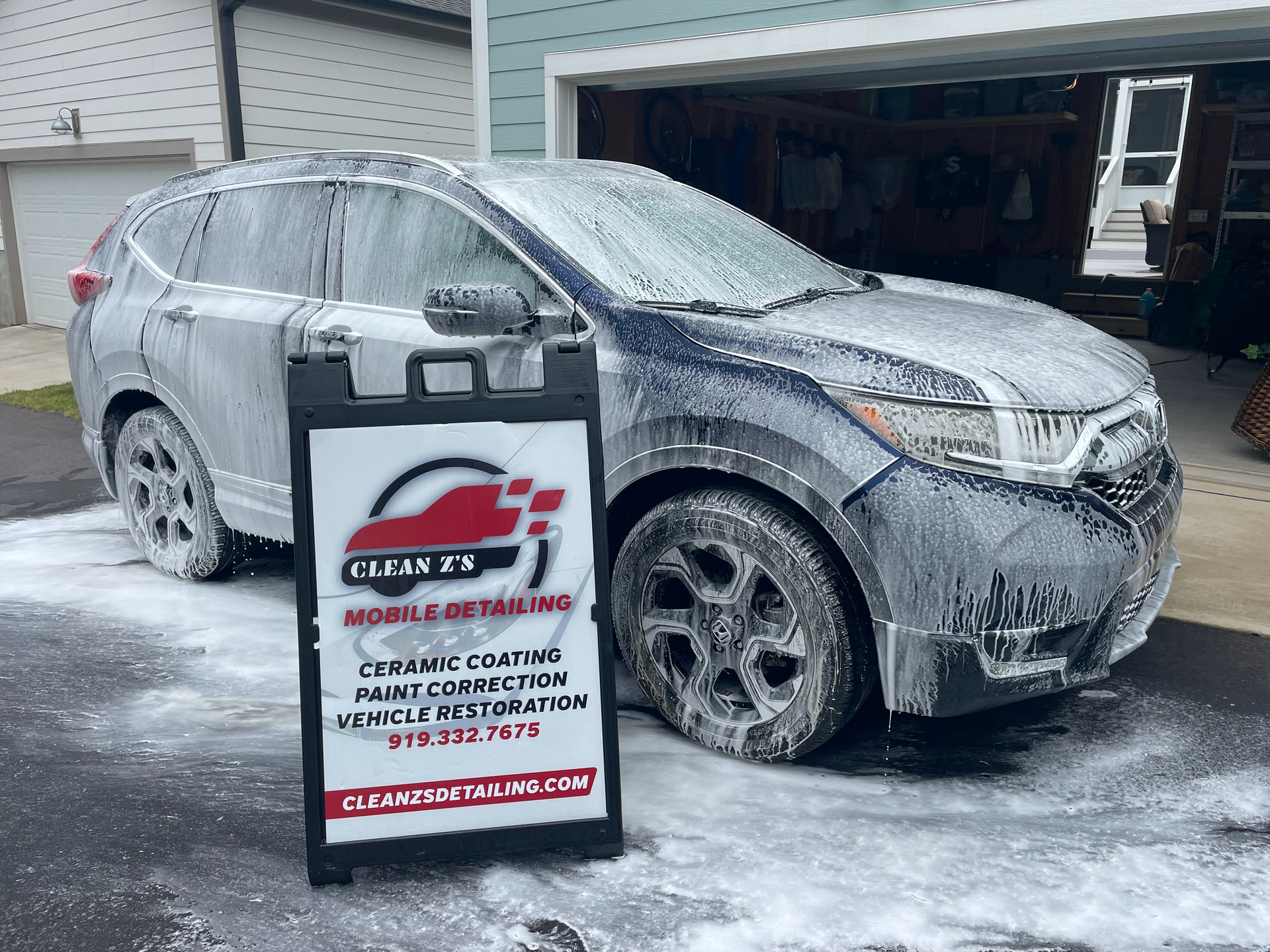 Gray Honda Accord parked in front of a sign for Clean 2's mobile detailing services.