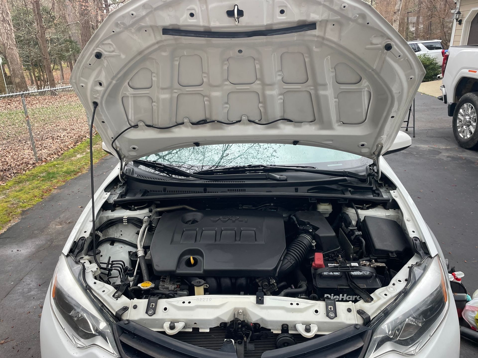 White Toyota Corolla with open hood, revealing the engine and its components.