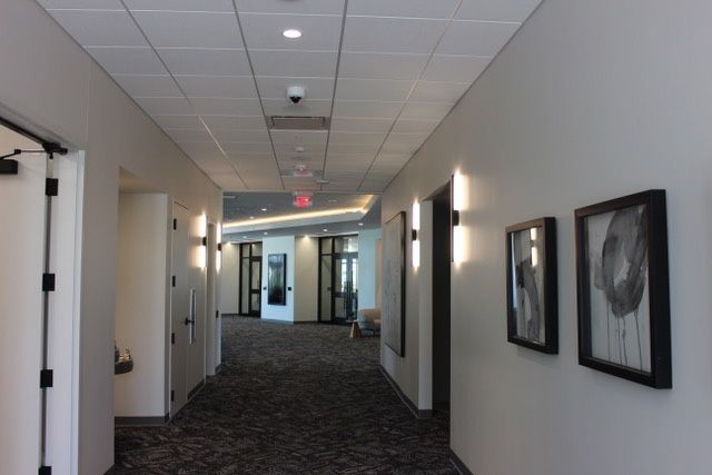 A hallway with pictures on the wall and a red exit sign