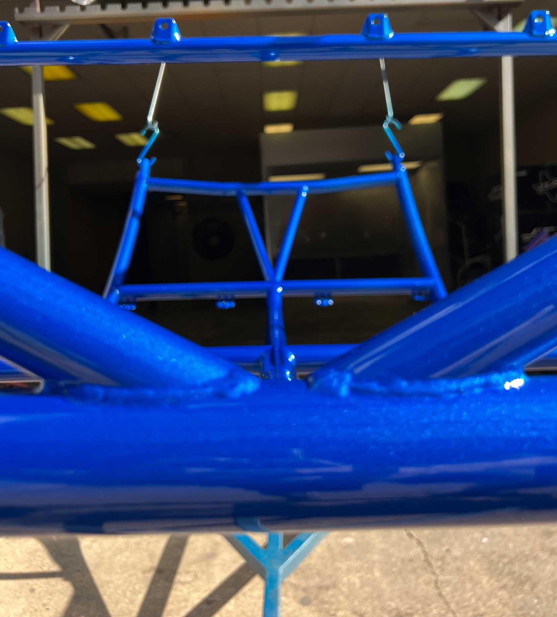 Blue metal frame, powder coated, hanging in a workshop.