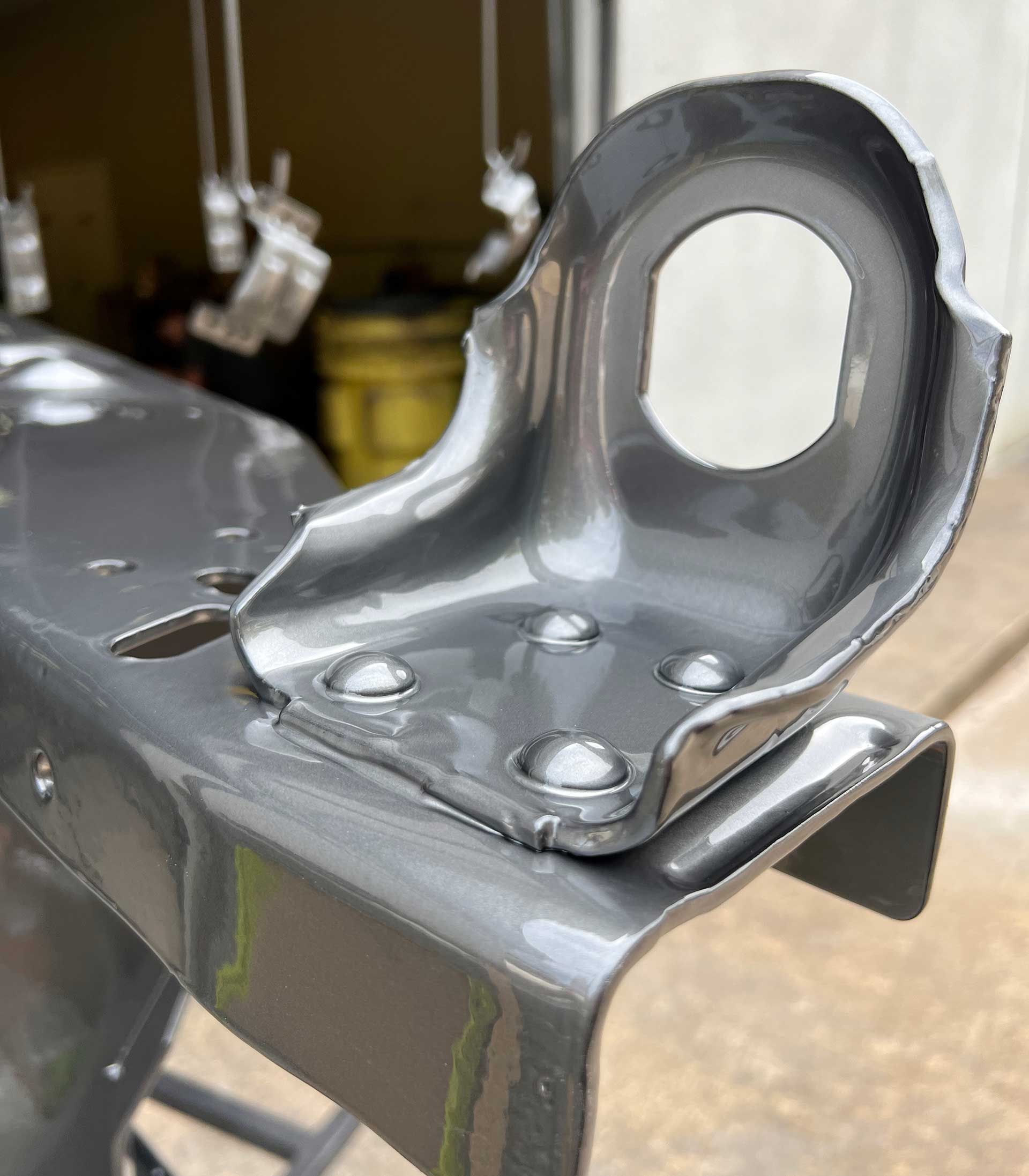 A close-up of a freshly painted, gray metal bracket attached to a frame.