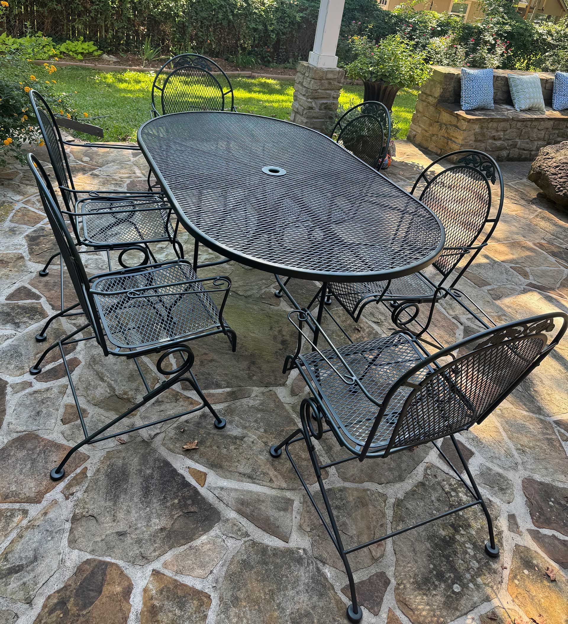 Black metal patio furniture set on stone patio, sunny outdoor setting.
