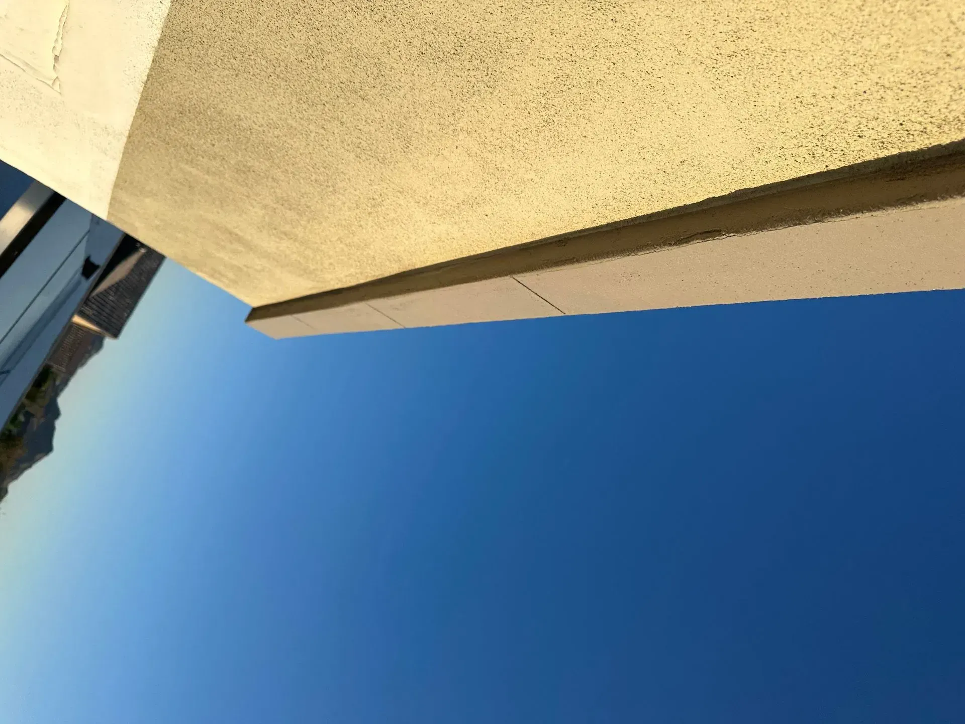 View of a light-colored building corner against a clear blue sky.