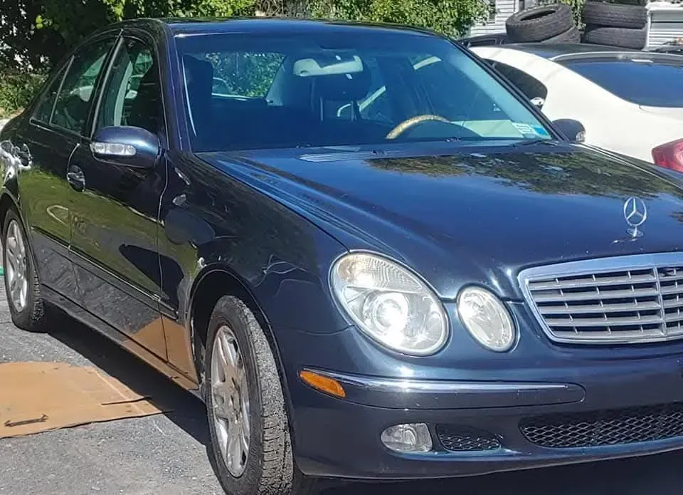 Dark blue Mercedes sedan parked outside on a sunny day.