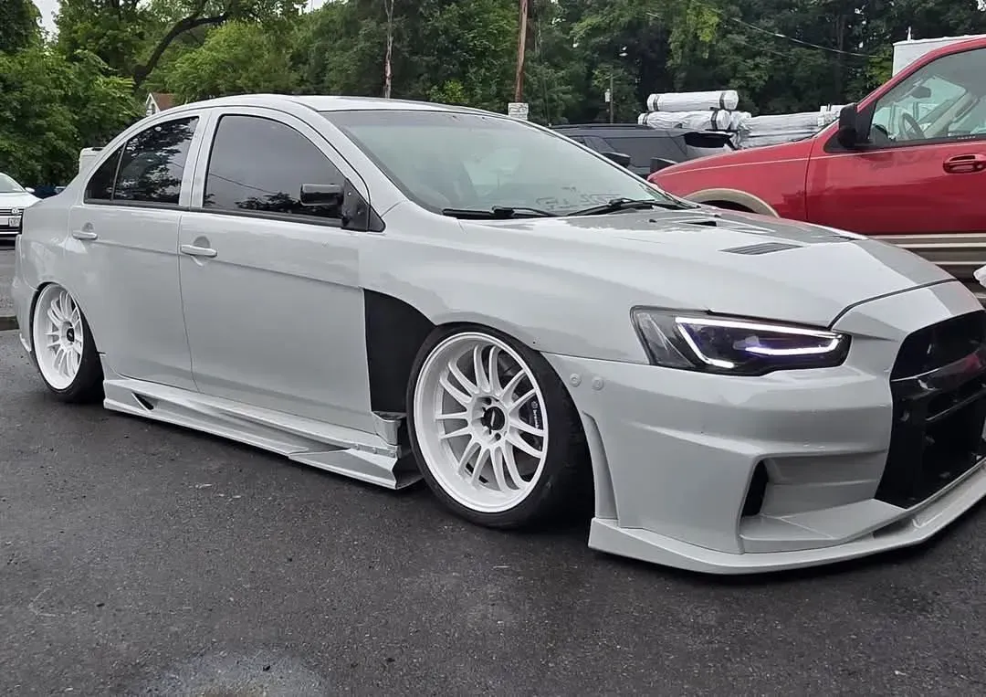 Gray modified Mitsubishi Lancer sedan with white wheels, low profile, and body kit.