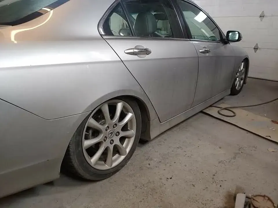 Silver car, partially visible in a garage. The car has silver rims, and is parked.