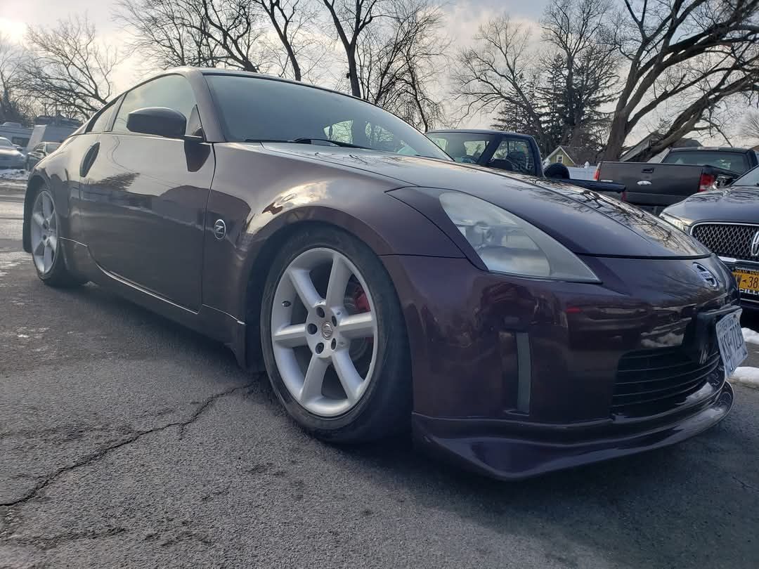 Dark purple Nissan 350Z sports car parked on asphalt with snow visible.