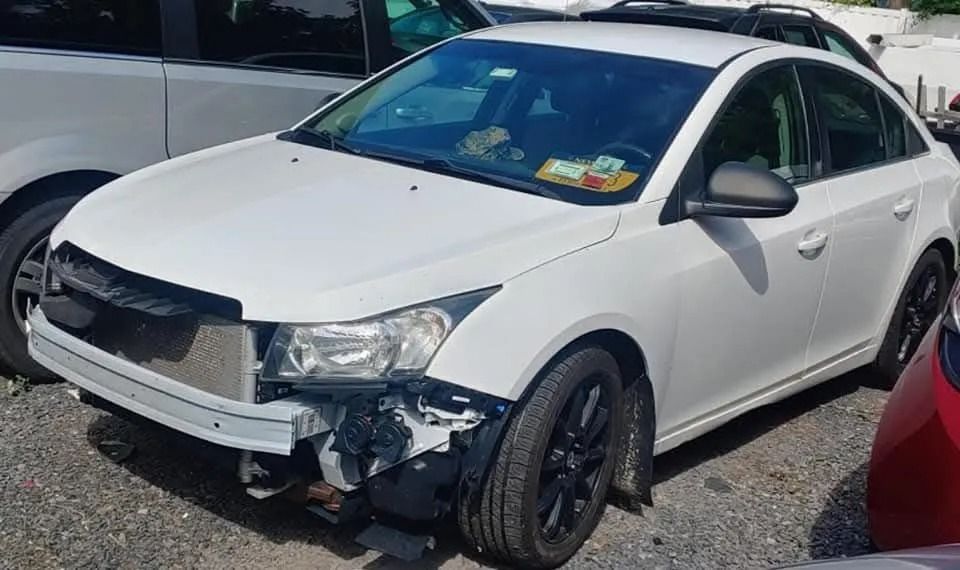 White Chevrolet Cruze with front-end damage parked outdoors.