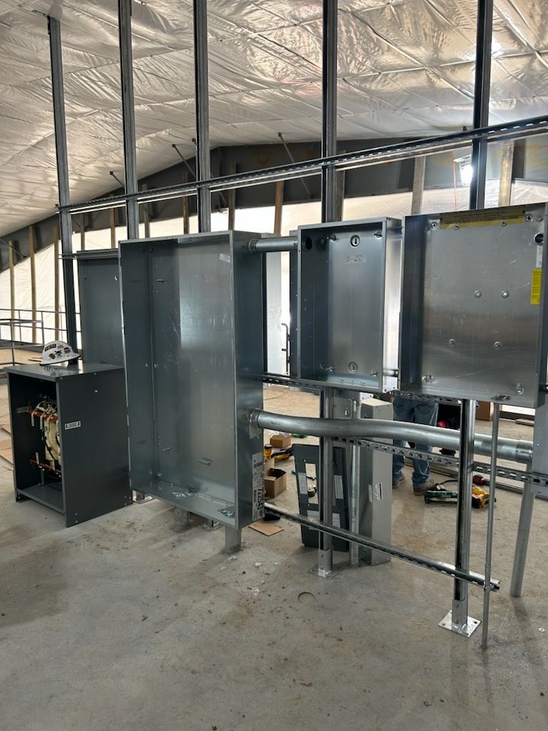 Industrial electrical panels and metal conduit installed in an unfinished building interior.