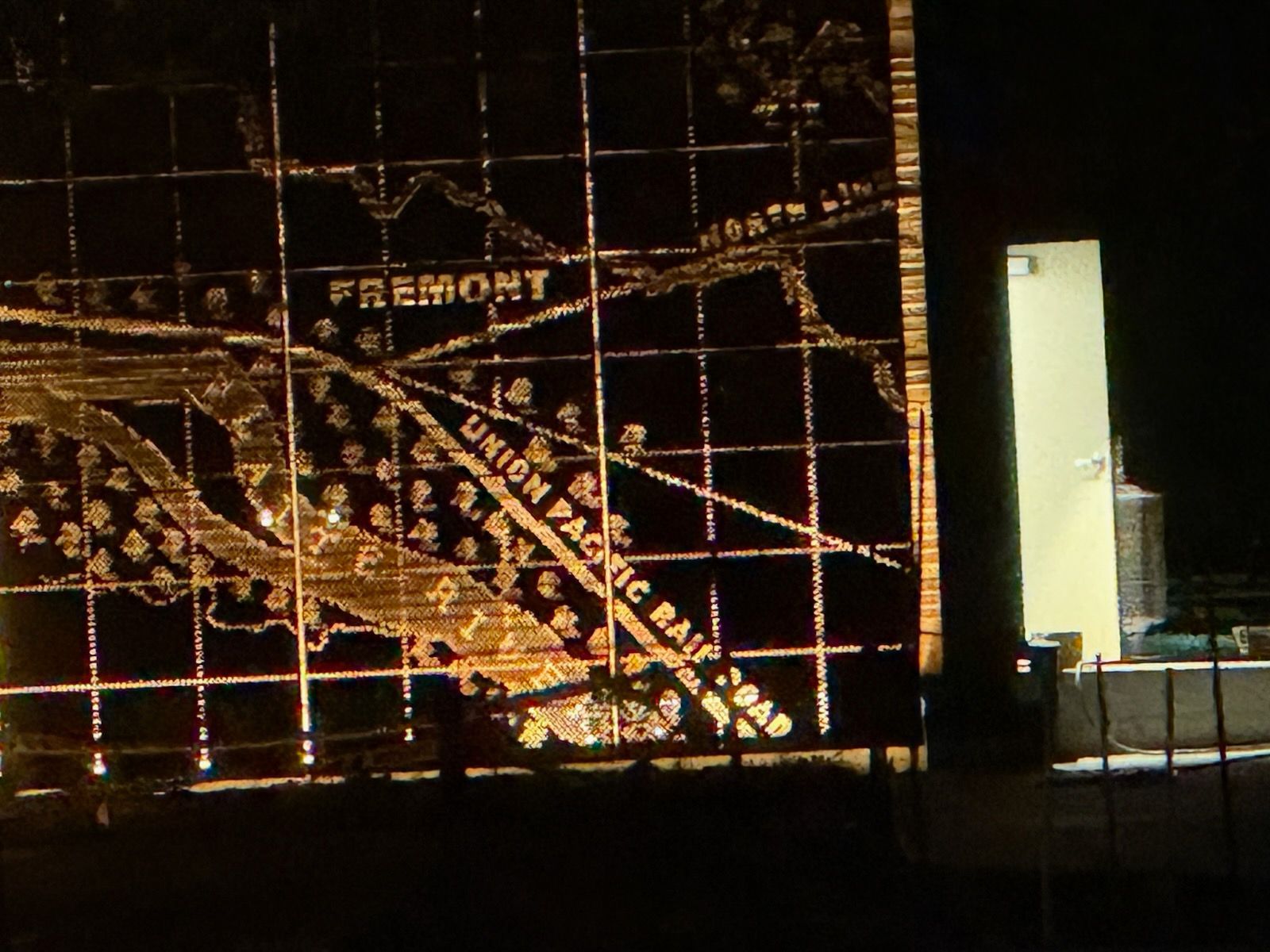 Nighttime view of a lit Fremont sign with a large decorative Christmas tree display in the foreground