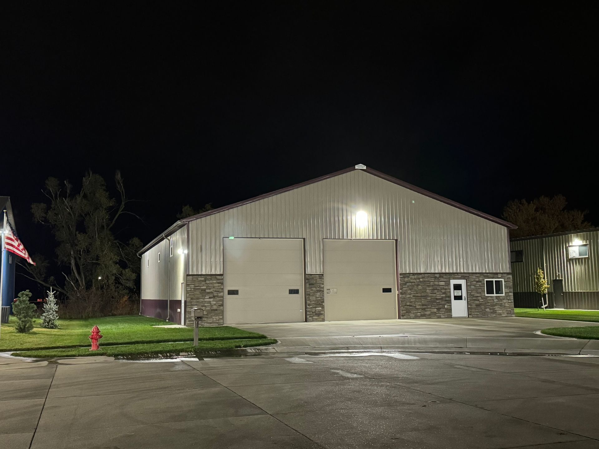 A large white building with a fire hydrant in front of it at night.