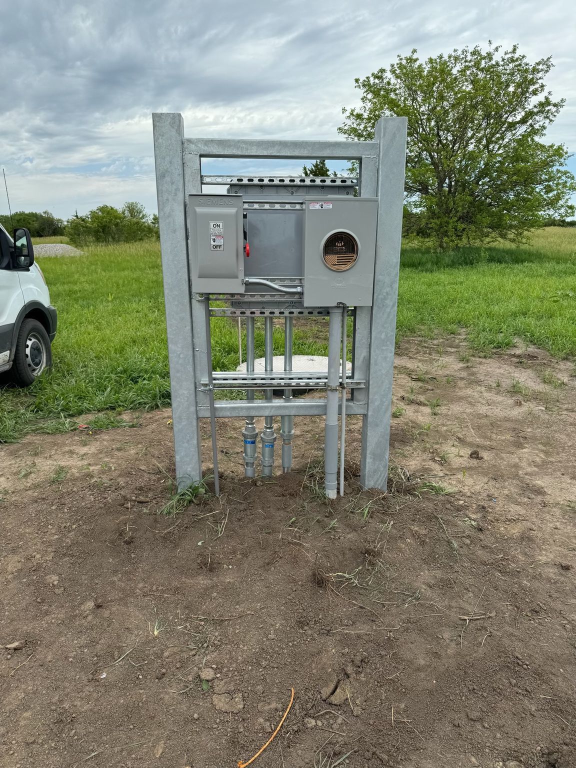 A large electrical box is sitting in the middle of a field.