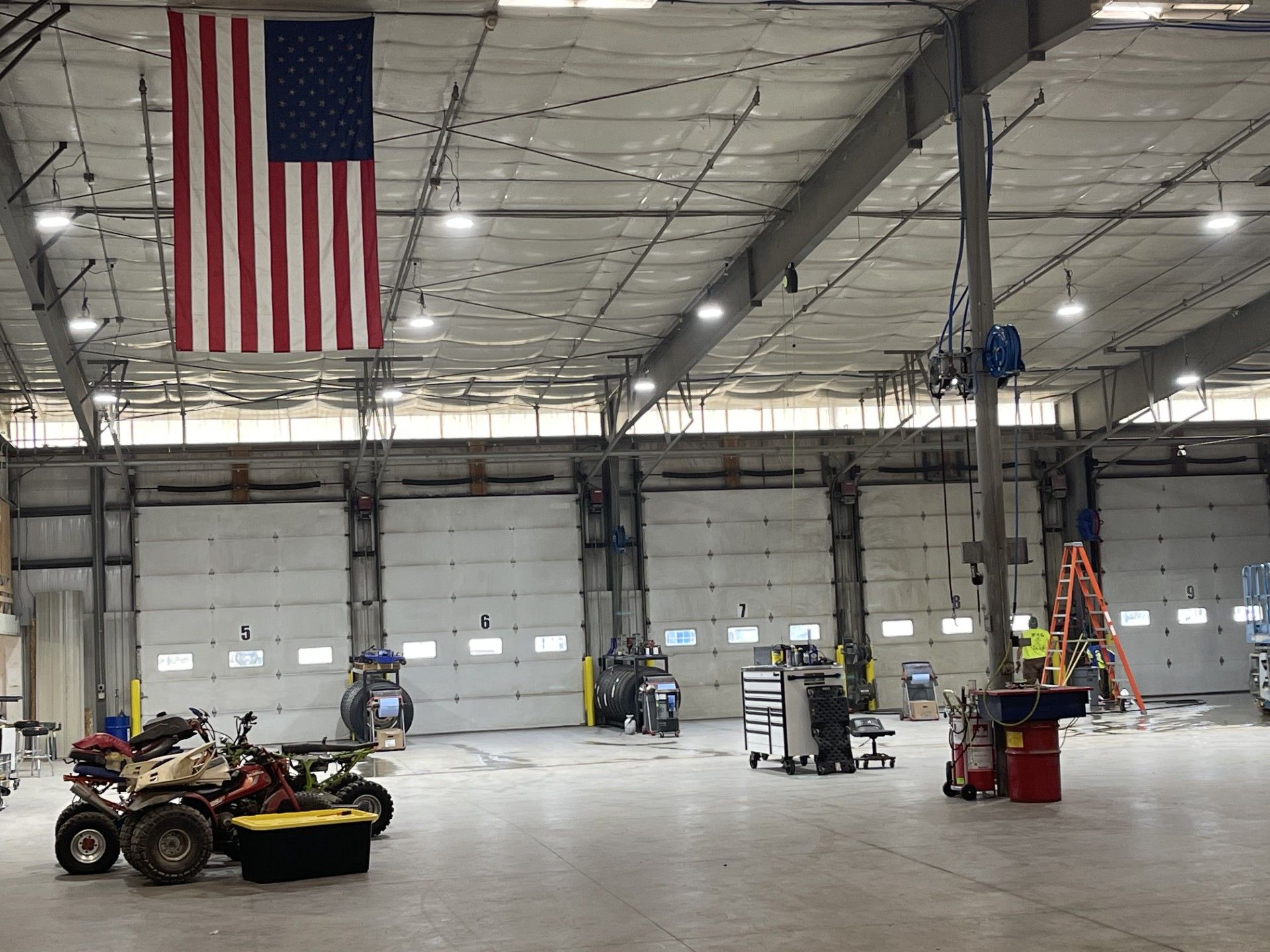 Large garage with American flag, tools, and vehicles.