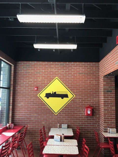 A restaurant with tables and chairs and a yellow sign on the wall