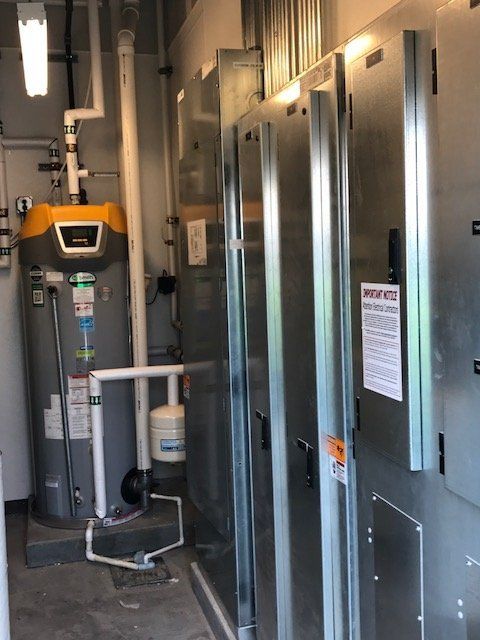 A room with a water heater and electrical panels