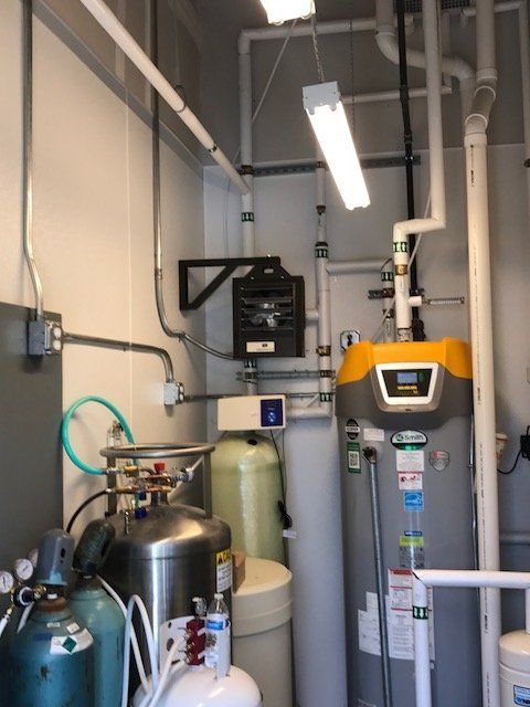 A room with lots of pipes and a water heater