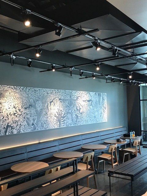 A restaurant with tables and chairs and a large painting on the wall