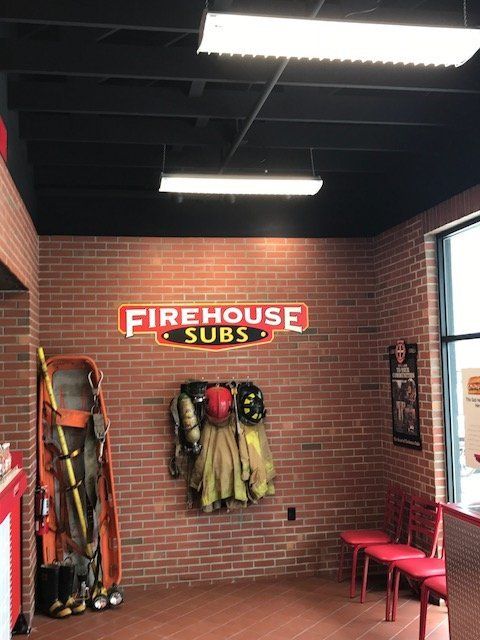 A firehouse subs sign hangs on a brick wall