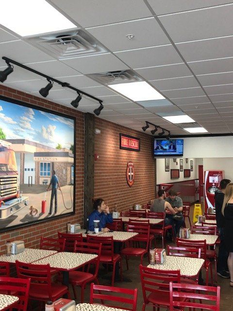The inside of a restaurant with red chairs and tables