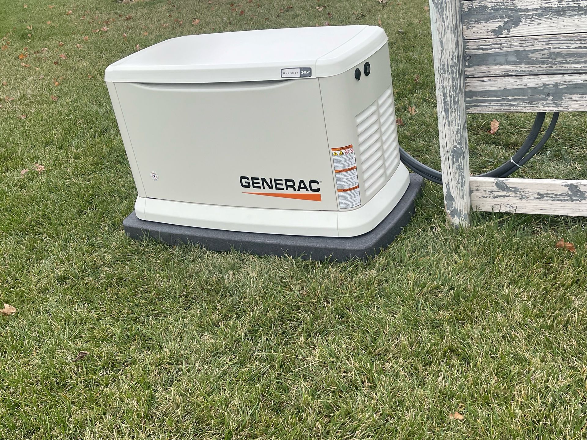 A generator is sitting on top of a lush green lawn next to a wooden bench.