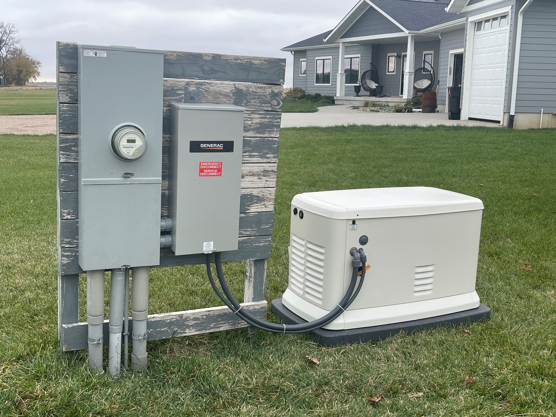 A generator is sitting in the grass in front of a house.