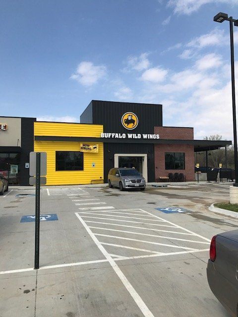 A car is parked in front of a buffalo wild wings restaurant