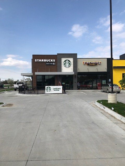 A starbucks coffee shop with a concrete driveway in front of it