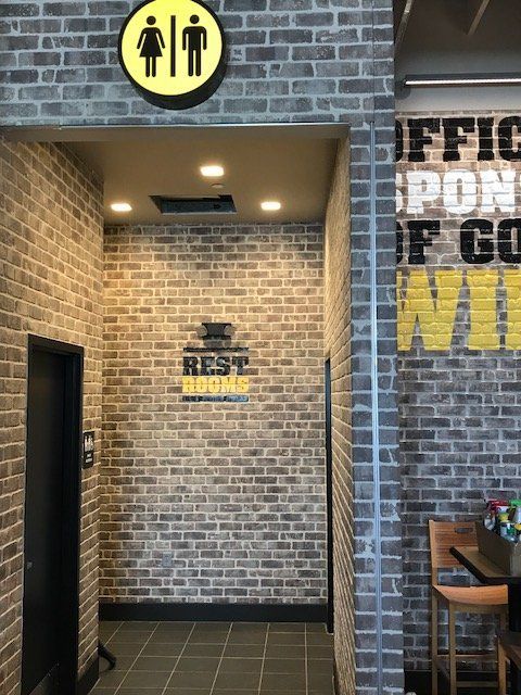 A brick wall with a sign on it that says restrooms.