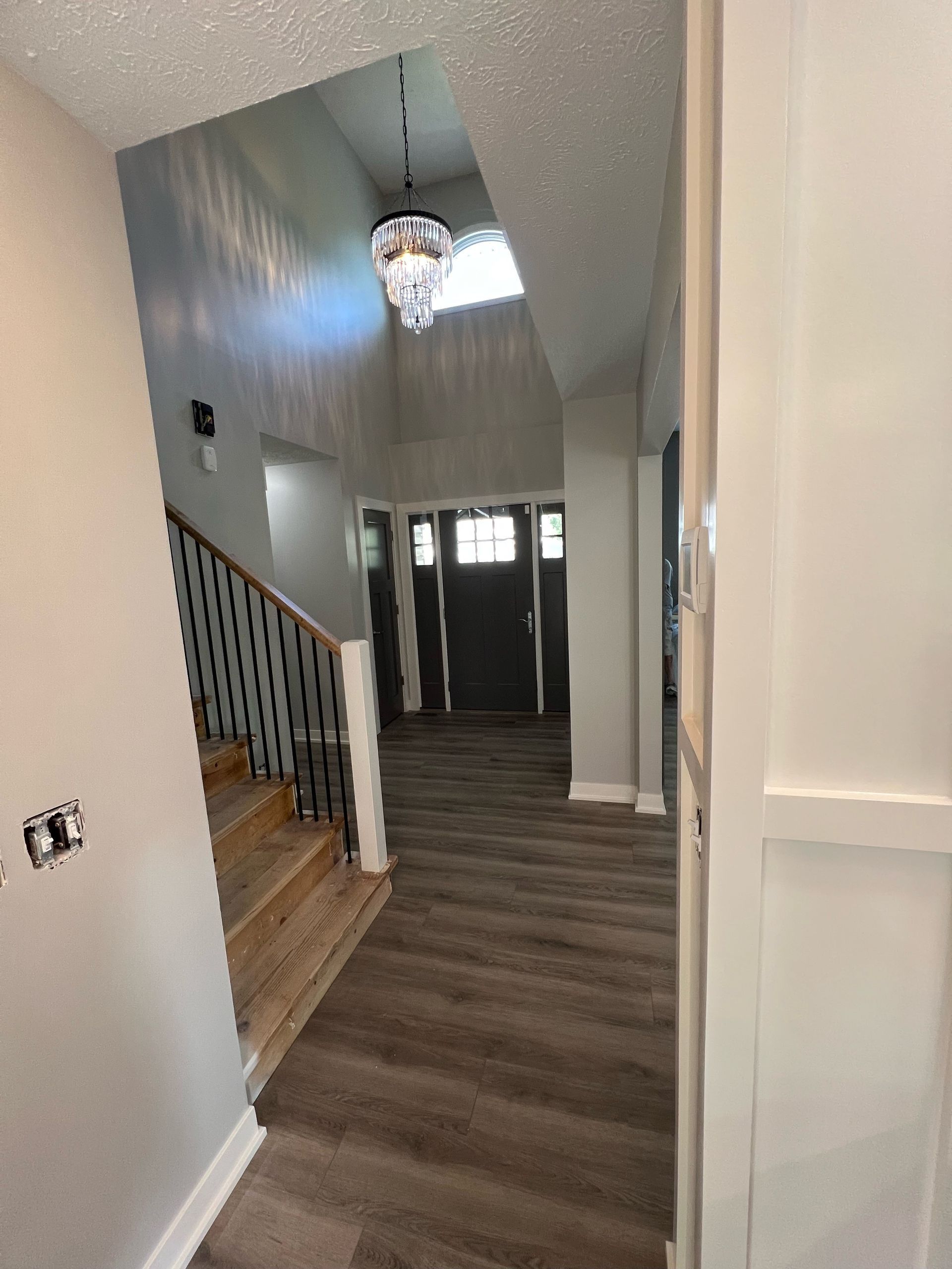 A hallway in a house with stairs and a chandelier hanging from the ceiling.