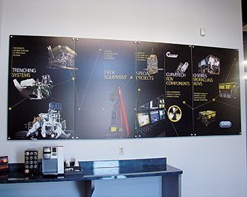 Large black wall display showcasing industrial equipment and company services with various images and text.